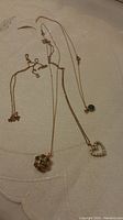Four yellow gold chains on fabric background, two with pendants