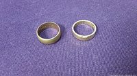Two rings side by side on purple fabric, flat top-down view showing overall appearance.