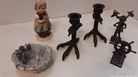Front view of Hummel figurine, metal candlesticks, metal figures, and geode bowl with metal bird accents