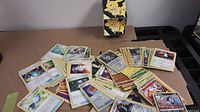 Spread out Pokemon cards showing multiple types and stages, including energy, trainer, and character cards with some cards face up displaying illustration and stats.