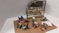 Overview of eight porcelain butterfly figurines arranged in front of the glass and brass display case.