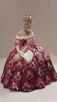 Front right side view of Royal Doulton figurine of a woman in pink floral dress holding a fan.