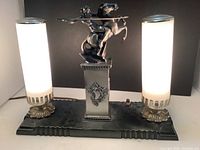 Front view of the lamp showing two illuminated frosted glass cylinder shades and central equestrian statue.