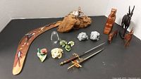 Collection of various small animal and decorative figures arranged with a boomerang and mini swords.