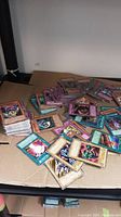Pile of various Yugioh trading cards showing several monster, spell, and trap cards spread loosely on a cardboard surface with some stacks of cards beside them.