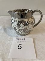Silver luster Wedgwood pitcher with floral grapevine decoration on white ceramic, showing front side profile.