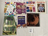 Photo showing 7 assorted craft books arranged on a surface, titles visible including bead jewelry, collage, and paper dolls among others.