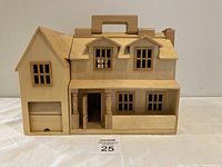 Front view of the wooden doll house showing closed position with windows, front porch, garage, and handle on top.