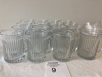 Heat resistant glass cups including sixteen matching with ribbed design and two unmatched glasses in a box.