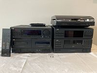Front view showing two black JVC stereo units stacked with a Kenwood turntable on top and a JVC remote control standing upright on the left side.