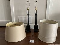 Photo showing two vintage lamps with old wiring and two large tapered drum lampshades placed in front of them.