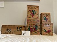 Front view of five wooden kitchen storage containers, four labeled for flour, sugar, tea, coffee, plus one divided container. Painted rooster motif on each.