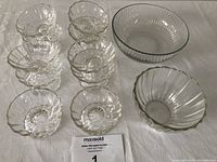 Twelve clear glass dishes displayed including 10 small sherbet/nappy dishes and 2 larger serving bowls showing shapes and designs.