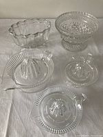 Set of 5 clear vintage glass items: 3 juice reamers arranged in front and the Jello mold with fruit bowl behind, displayed on a white background.