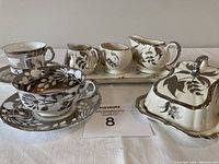 Front view showing assorted vintage Sandland Ware set and two fine china cups with saucers on white cloth background.