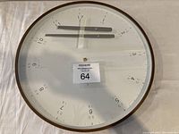Front view of large round wall clock, 19 inch diameter, showing numbers arranged unusually with clock hands taped to the face.