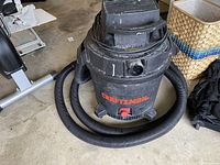 Full view of black Craftsman Shop Vac with attached hose coiled around base, showing the top and front areas, indicating overall used condition.