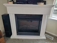 Full view of the freestanding electric fireplace unit showing white mantle and black insert.