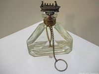 Full view of the clear glass bottle with embossed text on front and ship-shaped cork with attached chains and ring.