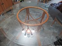 Overall view of the rattan table showing the round glass top and curved rattan frame beneath.