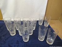 Overview of eleven crystal glasses arranged on dark fabric showing shape and number.