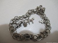 Full view of sterling silver charm bracelet showing chain style, heart links, and three animal charms including bear, horse with chariot, and turtle.