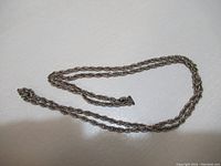 Full view of the sterling silver link necklace laid flat showing the entire length and twisting rope chain design.
