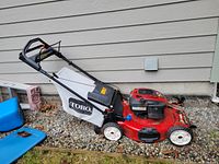 Side view showing red deck, white grass bag mounted and handle upright