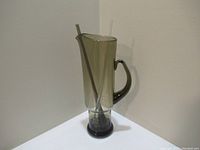 Full view of the vintage MCM-style glass pitcher with stir stick inside showing shape, handle and color.