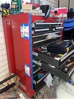 Front and side view of red Craftsman rolling tool chest with several drawers open and various items on top and inside