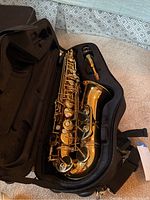 Jupiter alto saxophone resting inside its black soft carrying case with mouthpiece included in accessory compartment.