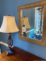 Overall view showing lamp and mirror side by side against blue wall, lamp includes wooden square base.