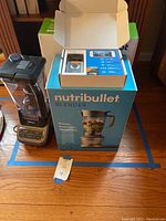 Grouped shot showing Ninja blender, Nutribullet blender box, Ring Video Doorbell packaging and iRobot Roomba box on floor.