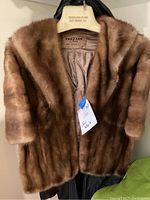 Full front view of the light brown fur stole hanging, showing the fur texture and length.