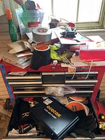 View of top of tool cabinet displaying various items including the AceTak car air pump case, duct tape, gloves, and assorted small tools and hardware.