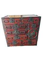 Front view showing chest with red lacquer finish, eight drawers, circular door and bird-motif metal hardware.