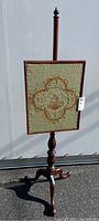 Full view of the wooden easel style needlework stand with embroidered panel featuring a unicorn crest design.
