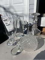 Photo showing the lot of two decanters and two vases grouped on a table under daylight, illustrating the relative sizes and glass clarity.