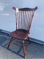 Side view of highback wooden chair showing shaped seat, turned legs, and spindle backrest with scroll detail on the top rail.