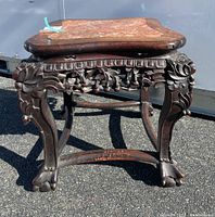 Front view of carved wooden side table with marble top