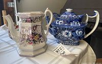 Both ceramic teapots displayed side by side, showing the multicolor floral design teapot missing its lid and the blue and white floral teapot with lid.