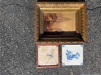 Full view showing Russells canvas board painting with ornate gold frame and two Dutch ceramic tiles underneath, one cracked.
