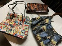 Three purses: multicolor printed tote, brown crocodile texture clutch, and black floral pattern purse