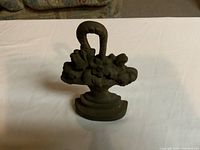 Front view of the cast iron floral basket door stop on a table surface, showing the detailed flower and leaf design.