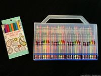 Top view of plastic carry case showing multiple crayons inside along with unopened 18-piece double-ended marker pack.