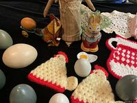 Photo showing vintage tin wind-up toys, knitted egg covers, wooden eggs, painted wooden bunny figure, and crochet linens.