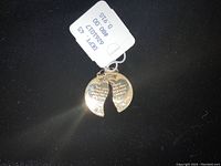 Front view of the closed gold charm pendant with visible inscriptions and price tag
