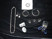Overview of jewelry items including necklace, multiple pairs of earrings, rings, and decorative pins on black background