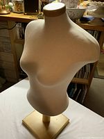 Front angle of the female torso dress form mannequin showing fabric cover and wooden neck cap and base.