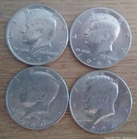Obverse side photo of four Kennedy half dollar coins dated 1972, 1979, 1980, and 1983 showing the profile of President John F. Kennedy and respective dates.